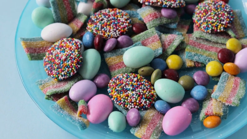 Različiti šareni slatkiši i bombone na tanjiru puni šećera