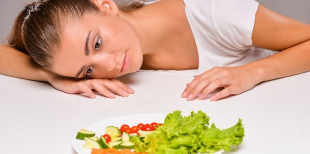 Žena posmatra tanjir sa povrćem kao simbol kontrole ishrane i procesa autofagije