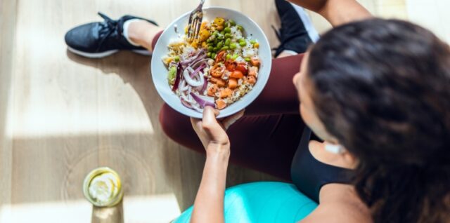 Osoba jede izbalansiran obrok sa povrćem, proteinima i ugljenim hidratima pre treninga