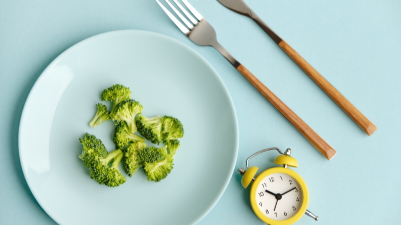 Prazan tanjir sa brokolijem i sat kao simbol fasting dijete i kontrolisanog unosa hrane